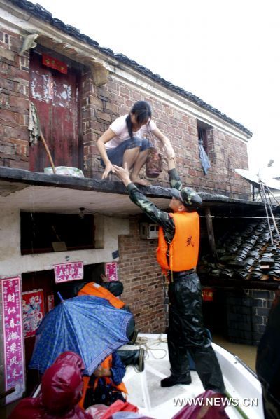 The armed policemen come to the aid of a deluge-beleaguered woman to transfer her towards the safety belt in a preemptive rescue operation against heavy rainfall, at Jintan Town, Ji'an City, east China's Jiangxi Province, June 20, 2010. 