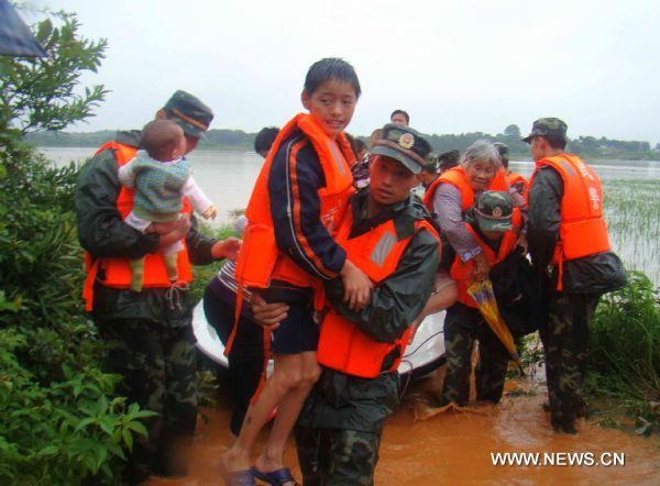 A squad of armed policemen from the No.1 detachment from the Jiangxi Provincial Corps of the Chinese People's Armed Police carry out the mission of transferring the deluge-beleaguered villagers towards the safety belt in their preemptive rescue operation against heavy rainfall, at Pingding Town, Yujiang County, east China's Jiangxi Province, June 20, 2010.