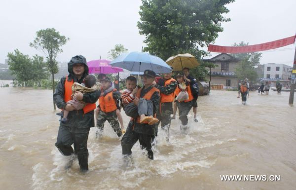 A squad of armed policemen carry the children towards the safety belt in their preemptive rescue operation against heavy rainfall, at Jintan Town, Ji'an City, east China's Jiangxi Province, June 20, 2010. 