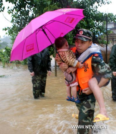 An armed policeman carries two kids to trudge towards the safety belt in a preemptive rescue operation against heavy rainfall, at Jintan Town, Ji'an City, east China's Jiangxi Province, June 20, 2010. 