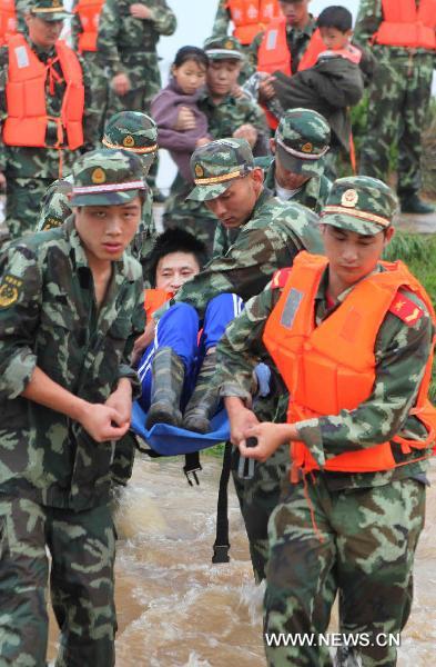 Paramilitary policemen help evacuate residents from Luozhen town of Fuzhou City, east China's Jiangxi Province, June 22, 2010.