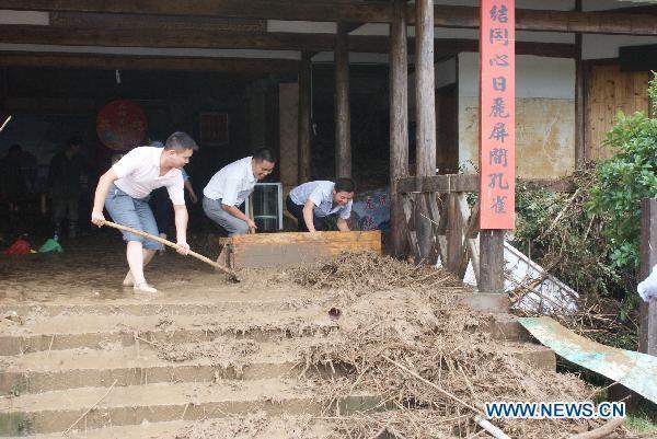 People clean up mud in the Longhushan scenery spot swept by floods in Yingtan of east China's Jiangxi Province, June 21, 2010.