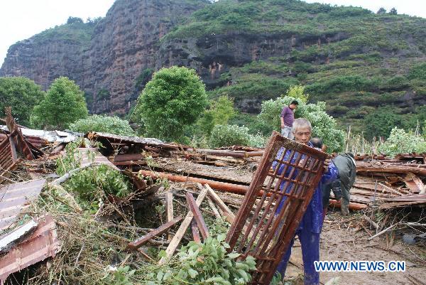 People clean up the collapsed houses in the Longhushan scenery spot swept by floods in Yingtan of east China's Jiangxi Province, June 21, 2010. 