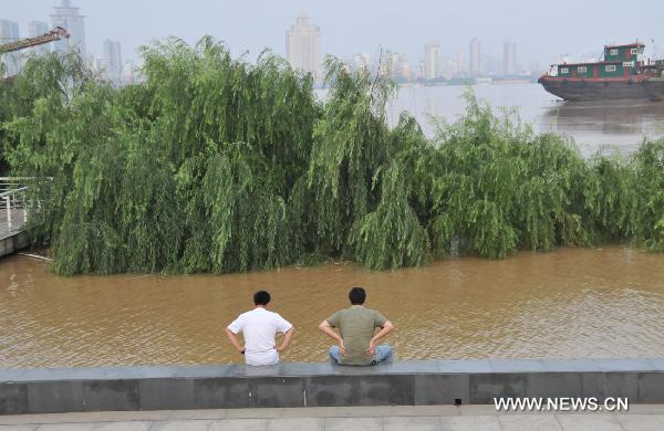 Two residents sit by the Ganjiang River as parts of the trees along the river is dunked by the flood, in Nanchang City, east China's Jiangxi Province, June 22, 2010.