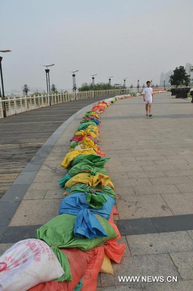 A resident walks along the sandbags in Qiushui Square located by the Ganjiang River, in Nanchang City, east China's Jiangxi Province, June 22, 2010. 