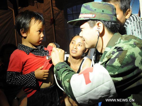 A military doctor examines a child affected by floods in a gymnasium serving as an evacuation center in Wuzhou City of east China's Jiangxi Province, June 23, 2010.