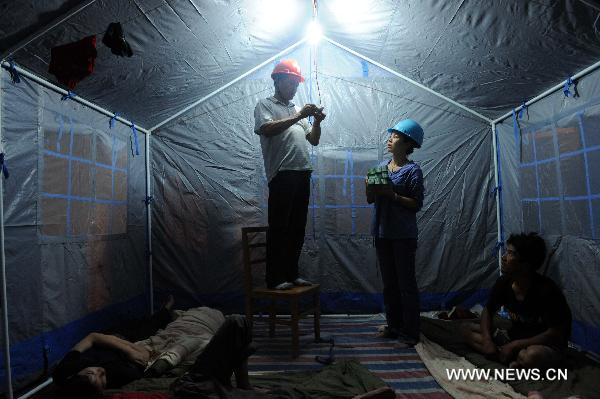 Electricians fix live wires in a makeshift tent serving for the people affected by floods in Wuzhou City of east China's Jiangxi Province, June 23, 2010.