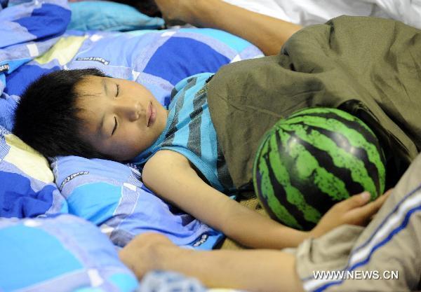 A child affected by floods sleeps in a gymnasium serving as an evacuation center in Wuzhou City of east China's Jiangxi Province, June 23, 2010.