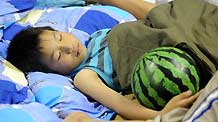 A child affected by floods sleeps in a gymnasium serving as an evacuation center in Wuzhou City of east China's Jiangxi Province, June 23, 2010.