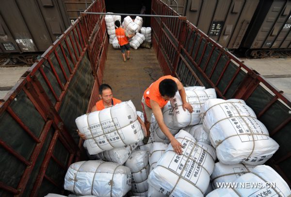 Workers load a train carriage with relief goods at a railway station in Wuhan, capital of central China&apos;s Hubei Province, June 23, 2010. 