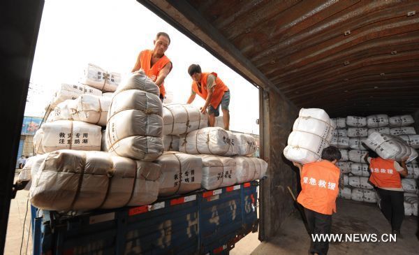 Workers load a train carriage with relief goods at a railway station in Wuhan, capital of central China&apos;s Hubei Province, June 23, 2010. 