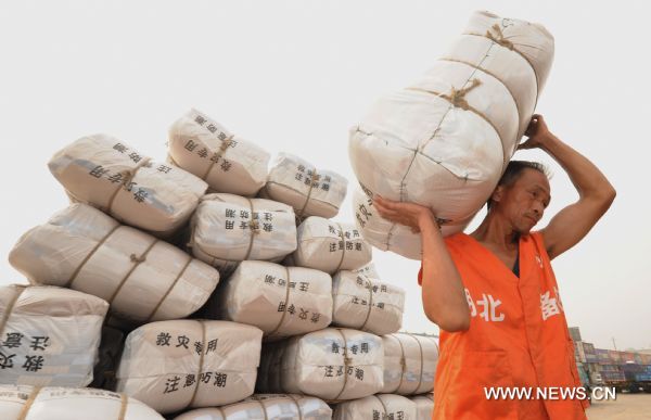 A work carries a pack of relif goods to load a train carriage at a railway station in Wuhan, capital of central China&apos;s Hubei Province, June 23, 2010. 