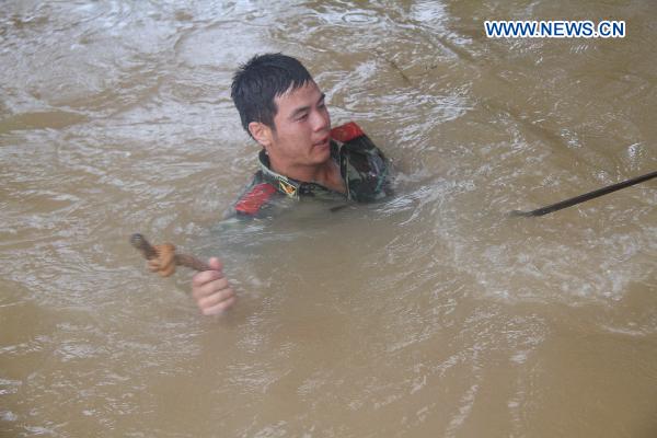 An armed policeman battles the torrents as a contingent of armed policemen with the Ji'an City's Detachment convey and pile up sand bags in a rush consolidation of the Fangzhou Batardeau to contain the tempestuous and surging Ganjiang River, at Liujiacun section, in Ji'an City, east China's Jiangxi Province, June 24, 2010. 