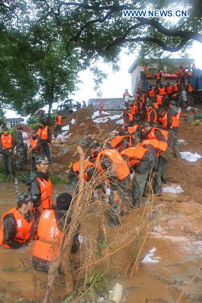 A contingent of armed policemen with the Ji'an City's Detachment convey and pile up sand bags in a rush consolidation of the Fangzhou Batardeau to contain the tempestuous and surging Ganjiang River, at Liujiacun section, in Ji'an City, east China's Jiangxi Province, June 24, 2010.