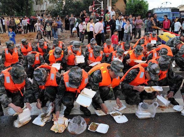 Armed police have a quick meal during a rescue operation in Malong County of southwest China's Yunnan Province June 26, 2010.