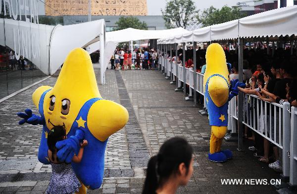 Staff members dressed as the mascot of the Europe Union (EU) pose in front of the visitors who queue up to enter the Belgium/EU Pavilion at the Shanghai World Expo in Shanghai, east China, June 27, 2010.