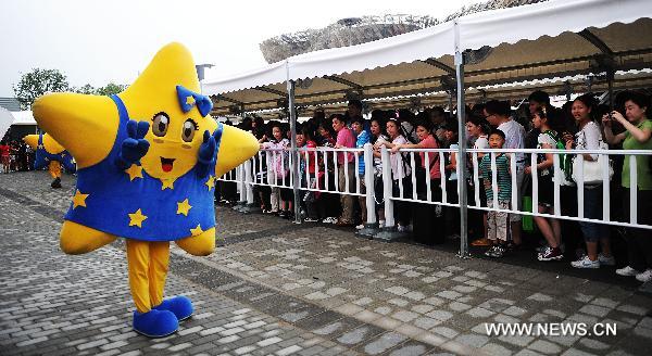 A staff member dressed as the mascot of the Europe Union (EU) poses in front of the visitors who queue up to enter the Belgium/EU Pavilion at the Shanghai World Expo in Shanghai, east China, June 27, 2010. 