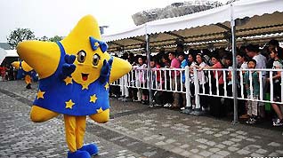 A staff member dressed as the mascot of the Europe Union (EU) poses in front of the visitors who queue up to enter the Belgium/EU Pavilion at the Shanghai World Expo in Shanghai, east China, June 27, 2010.