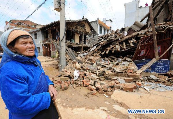 A woman stands near her damaged house in Malong County of southwest China&apos;s Yunnan Province, June 27, 2010.