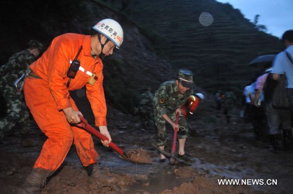 Soldiers try to clear a road covered by mud after a landslide in Guanling County of southwest China's Guizhou Province, on June 28, 2010. 