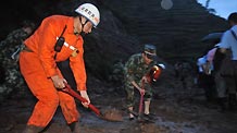 Soldiers try to clear a road covered by mud after a landslide in Guanling County of southwest China's Guizhou Province, on June 28, 2010.