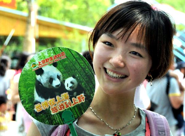 A girl shows up a souvenir fan as pandas meet the visitors, at the World Expo Pandas Pavilion inside the Shanghai Wild Animal Park in its opening day, in Shanghai, east China, June 30, 2010.
