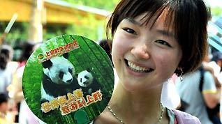 A girl shows up a souvenir fan as pandas meet the visitors, at the World Expo Pandas Pavilion inside the Shanghai Wild Animal Park in its opening day, in Shanghai, east China, June 30, 2010.