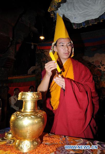 Bainqen Erdini Qoigyijabu, the 11th Panchen Lama, and also vice president of the Buddhist Association of China, takes a silk bag out of the golden urn for the reincarnation of the 5th Living Buddha Dezhub in Lhasa, capital of southwest China&apos;s Tibet Autonomous Region, on July 4, 2010.