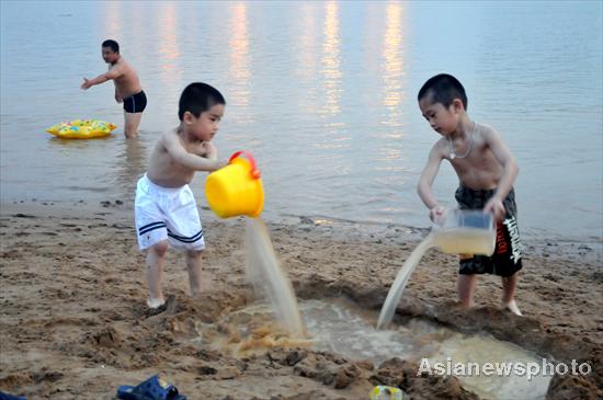  Two children play with water at the bank of the Minjiang River in Fuzhou in East China's Fujian province, July 3, 2010. [China Daily/Asianewsphoto]