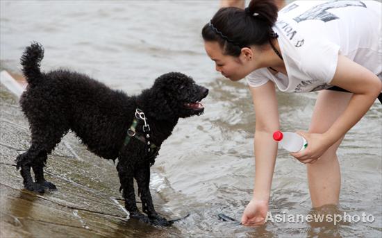 A woman plays with her dog at a park by the Hanjiang River in Wuhan, Central China's Hubei province, July 3, 2010. [China Daily/Asianewsphoto]