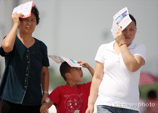  Visitors shield themselves from the sun with paper sheets in the Beijing Olympic Park on July 4, 2010. [China Daily/Asianewsphoto]