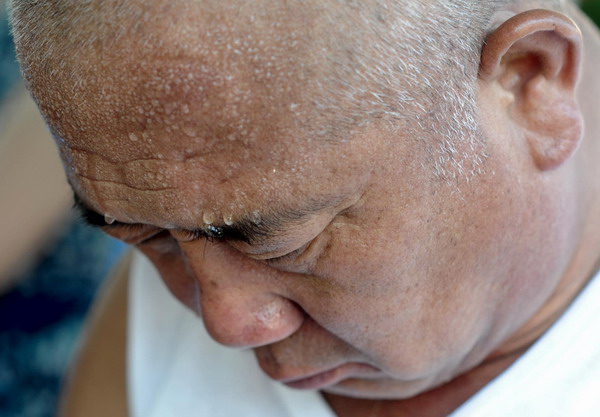 A man, wet with sweat, takes a nap on a bus in Jinan, east China's Shandong Province on July 6, 2010.