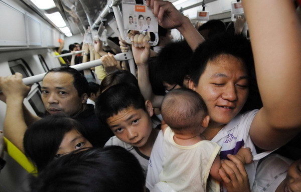 A man cradles his baby in his arms as commuters shove each other in a crowded train on a subway line in Beijing July 14, 2010. 