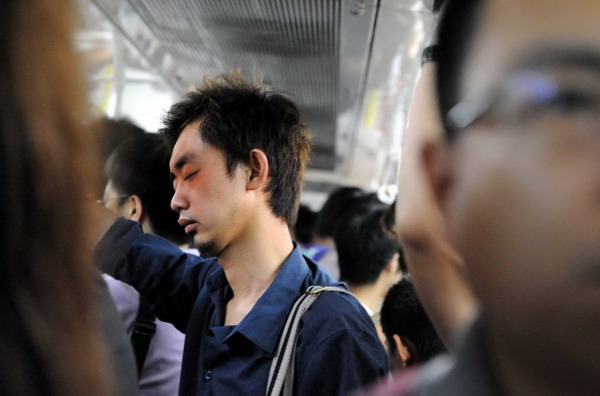 A man takes a nap in an over-crowded train on subway Line 1 in Beijing, July 14, 2010. 