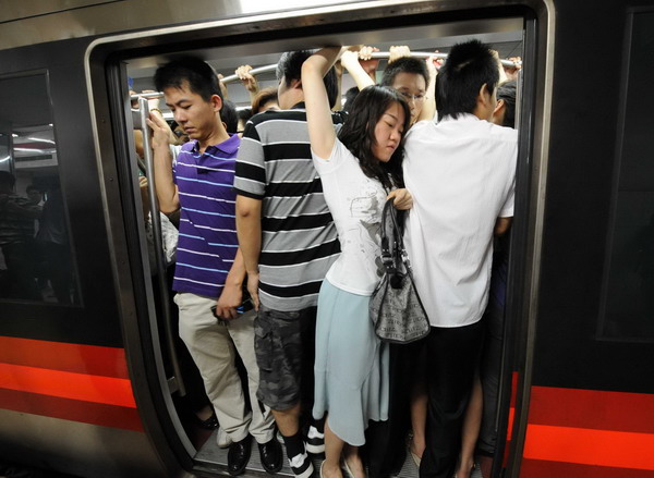 Commuters try hard to squeeze into a train at a stop on subway Line 1 in Beijing, July 14, 2010.