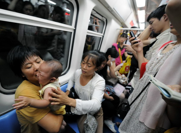 A baby cries in a crowded train on subway Line 1 in Beijing, July 14, 2010.