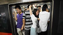 Commuters try hard to squeeze into a train at a stop on subway Line 1 in Beijing, July 14, 2010.
