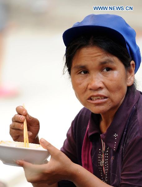 A woman takes food as she attends a fair in Xiaohe Town of Qiaojia County, southwest China's Yunnan Province, July 15, 2010. 