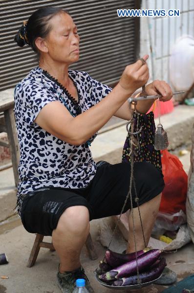 A woman takes food as she attends a fair in Xiaohe Town of Qiaojia County, southwest China's Yunnan Province, July 15, 2010. 