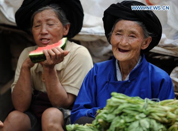 Two old women attend a fair in Xiaohe Town of Qiaojia County, southwest China's Yunnan Province, July 15, 2010. 