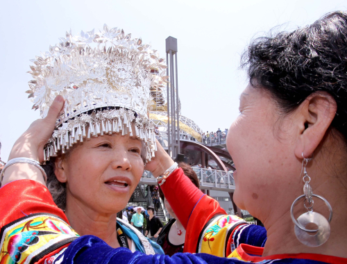 A woman of the Miao nationality puts a traditional headpiece on Tomiyo Yamada at the Expo Park May 1.