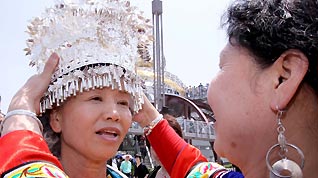 A woman of the Miao nationality puts a traditional headpiece on Tomiyo Yamada at the Expo Park May 1.