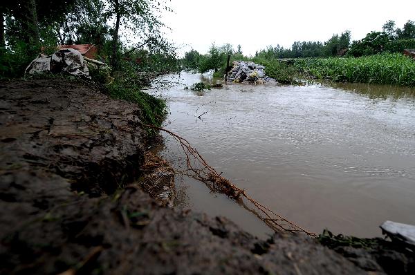 Water run through the burst on the levee of the Shengli River in Tieling County, north China's Liaoning Province, July 21, 2010. 