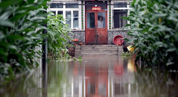 A woman looks at the flood around her house in Tieling County, north China's Liaoning Province, July 21, 2010.