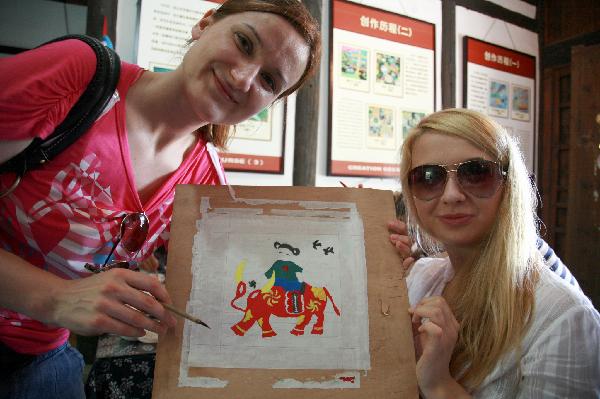 Foreign visitors show up a rural painting drawn by themselves in Fengjing Township in east China's Shanghai, July 22, 2010. 