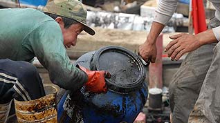 Fishermen unload a barrel of crude oil collected during the oil spill cleanup operation off the coast of Dalian City, northeast China's Liaoning Province, July 22, 2010.