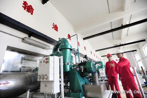 Workers examine the machines in Dalian branch of China National Petroleum Corporation (CNPC) in Dalian, northeast China's Liaoning Province, July 23, 2010.