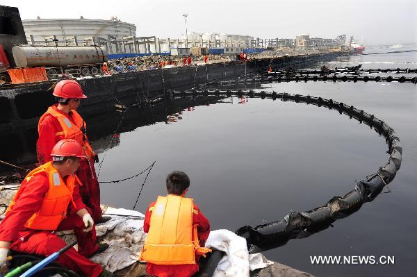 Workers of China National Petroleum Corporation (CNPC) keep sight of the polluted oil discharge area in Dalian, northeast China's Liaoning Province, July 23, 2010. 