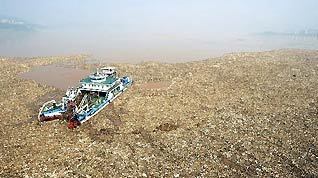 A litter-cleaning vessel collects floating garbage in front of the Three Gorges Dam in Yichang, central China's Hubei Province, July 28, 2010. Emergency cleaning measures were initiated by related departments to clear the large amount of floating garbage brought by the second flood peak of the Yangtze River Wednesday.