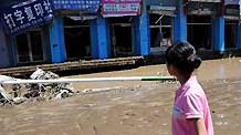 A girl looks at a flood-ravaged street in Kouqian Township of Yongji County, northeast China's Jilin Province, July 29, 2010.